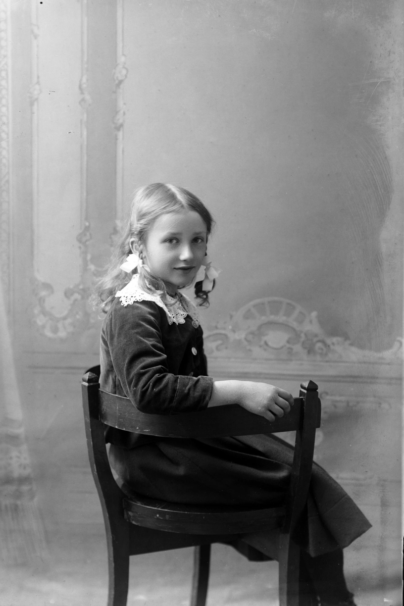 Studioportrett av en liten jente som sitter.