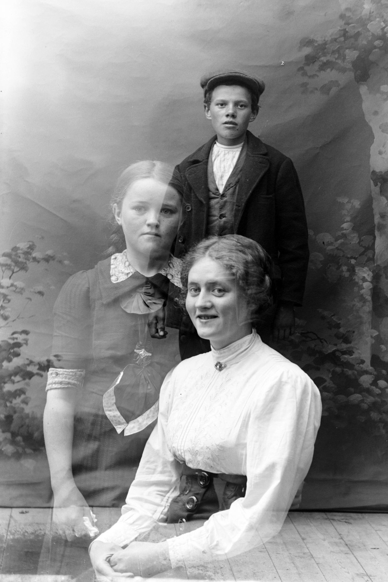 Studioportrett av en kvinne og to barn.