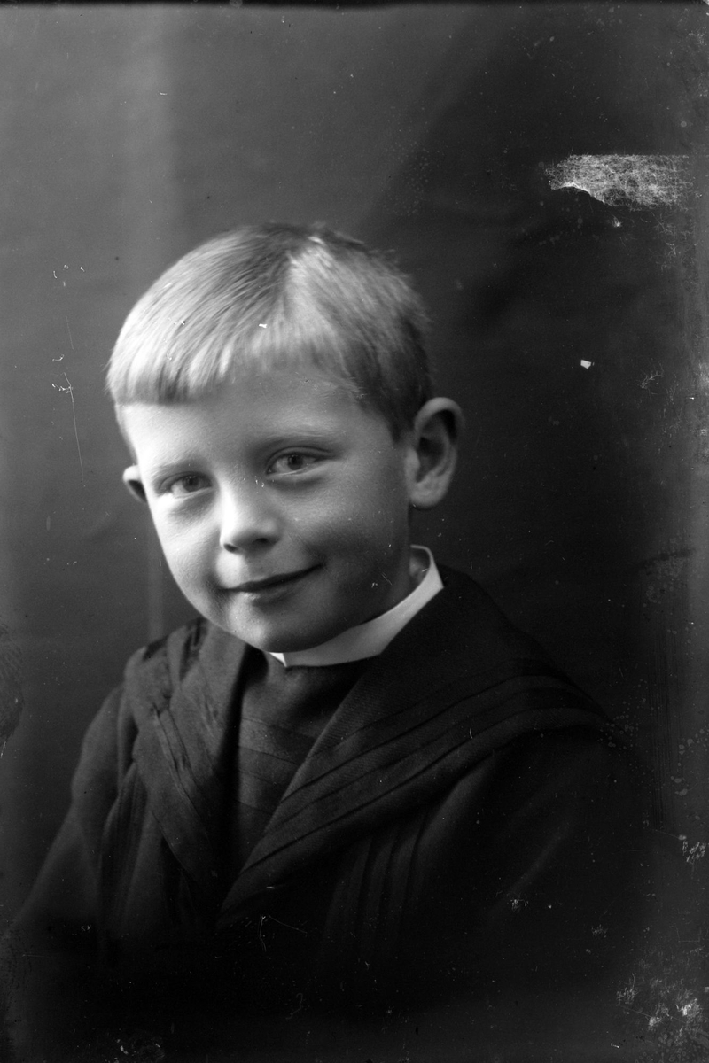 Studioportrett av en ung gutt i halvfigur.