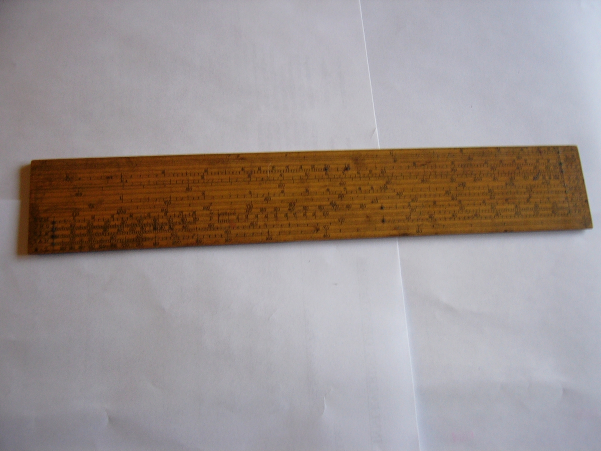 En 35 cm. lang linjal av tre med mange skalaer for avlesing.
