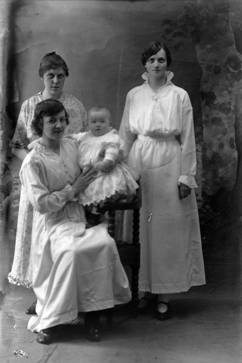 Studioportrett av tre kvinner med et lite barn.