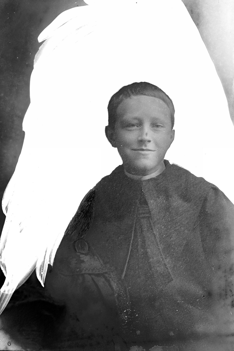 Studioportrett av en gutt foran en hvit, retusjert bakgrunn.