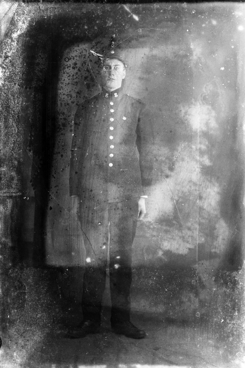 Studioportrett av en mann i uniform. Bildet er ganske ødelagt.