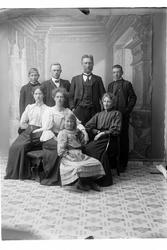 Studioportrett i helfigur av en gruppe på åtte personer.