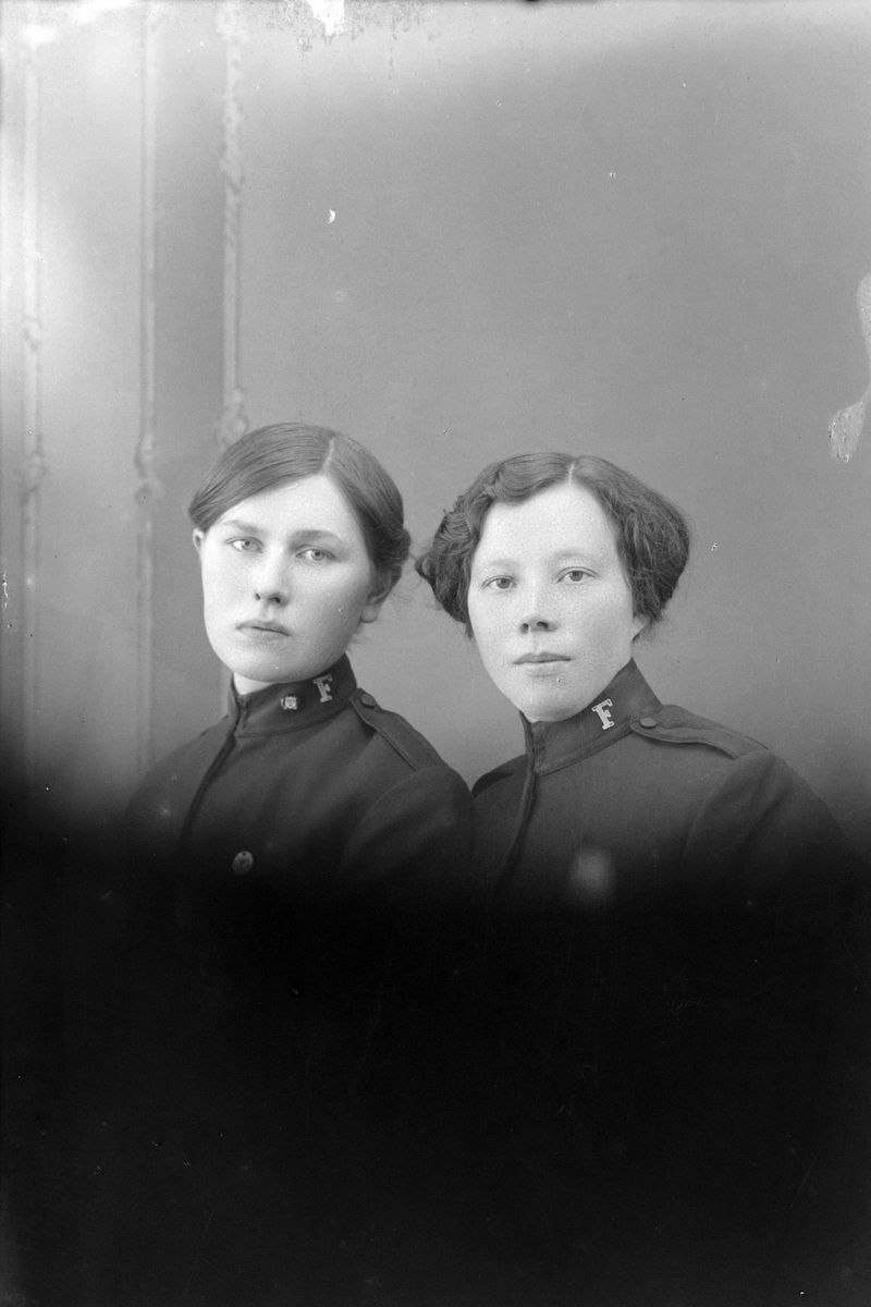 Studioportrett av to kvinner kledd i uniformer.