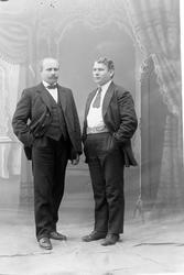 Studioportrett av to menn i helfigur.