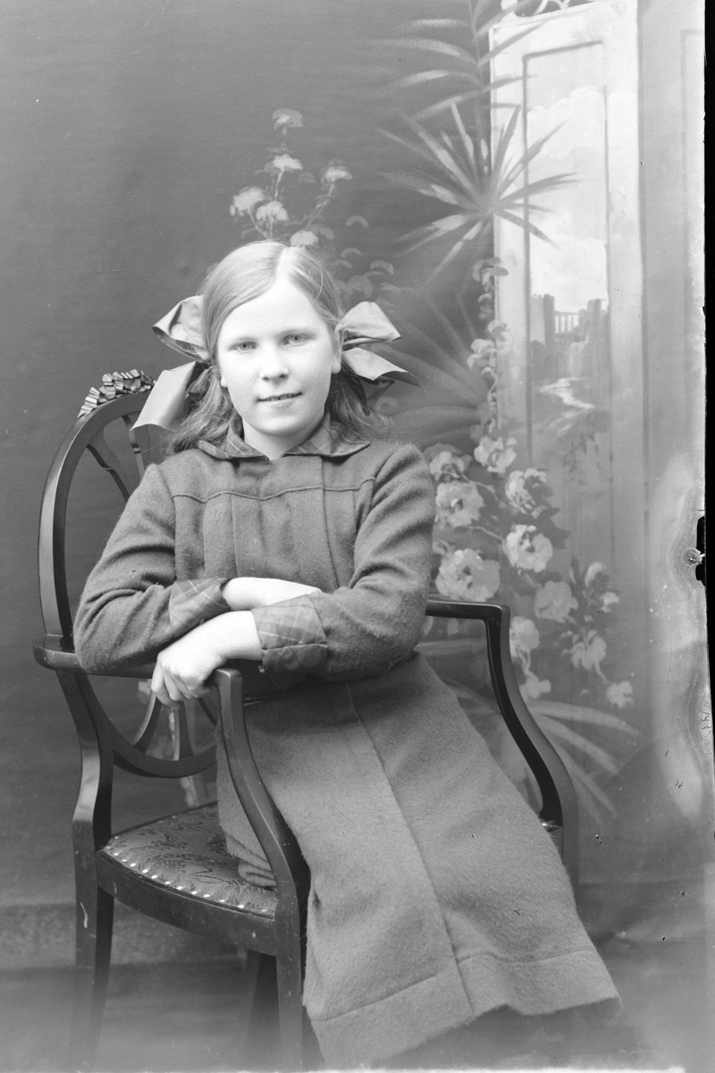 Studioportrett av en ung jente sittende på en stol.