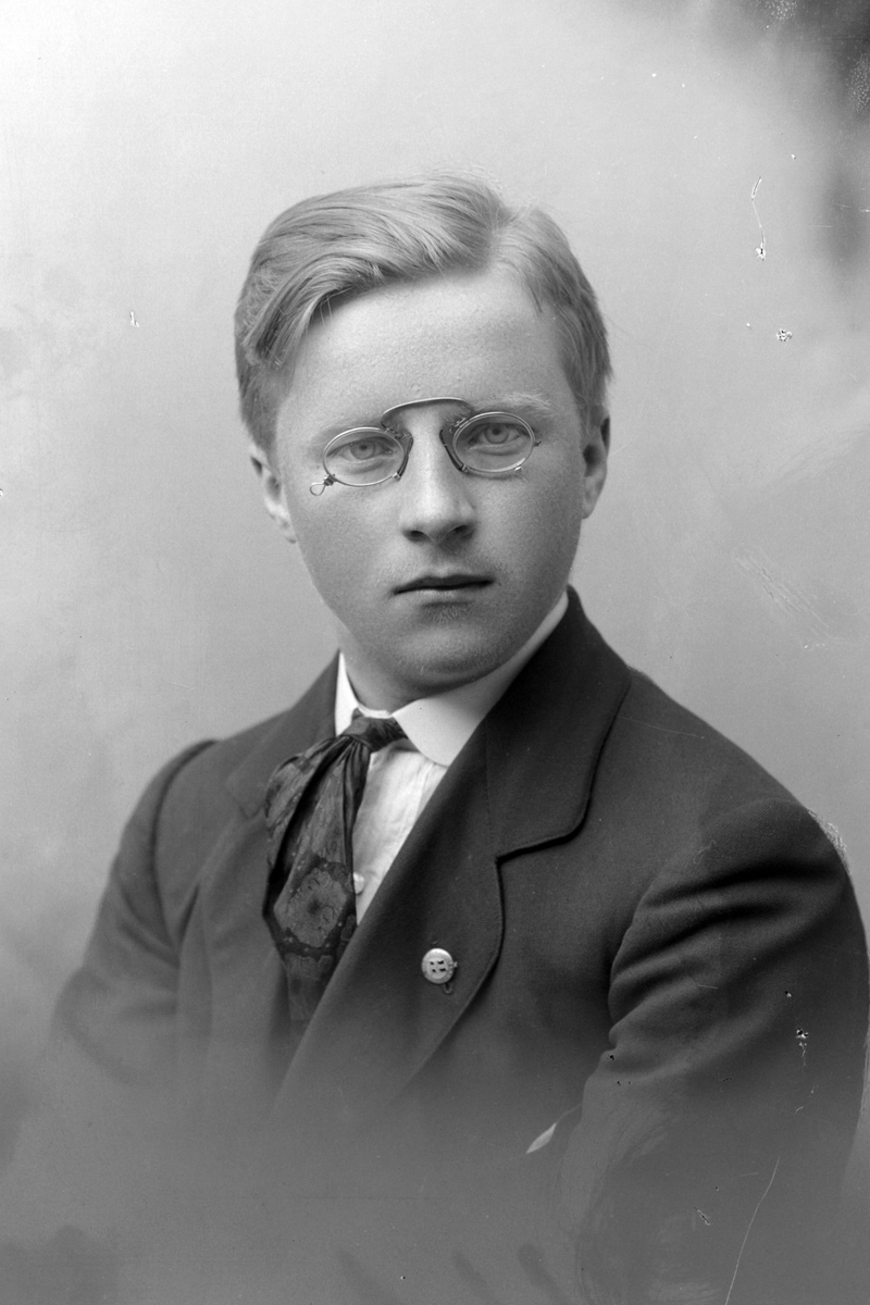 Studioportrett av en ung mann med briller.