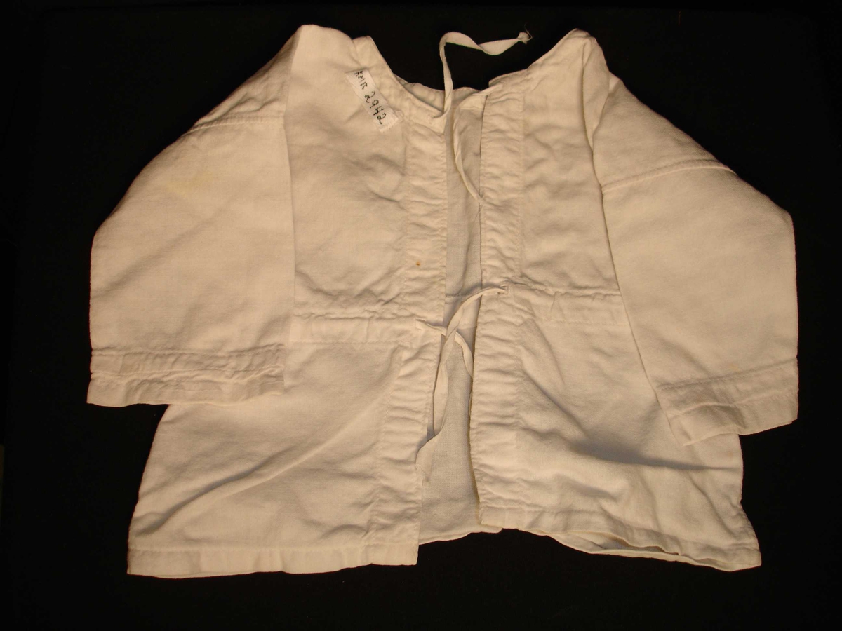 Babyskjorte i hvit bomull, uten krage og med snøring i hals og i midjen