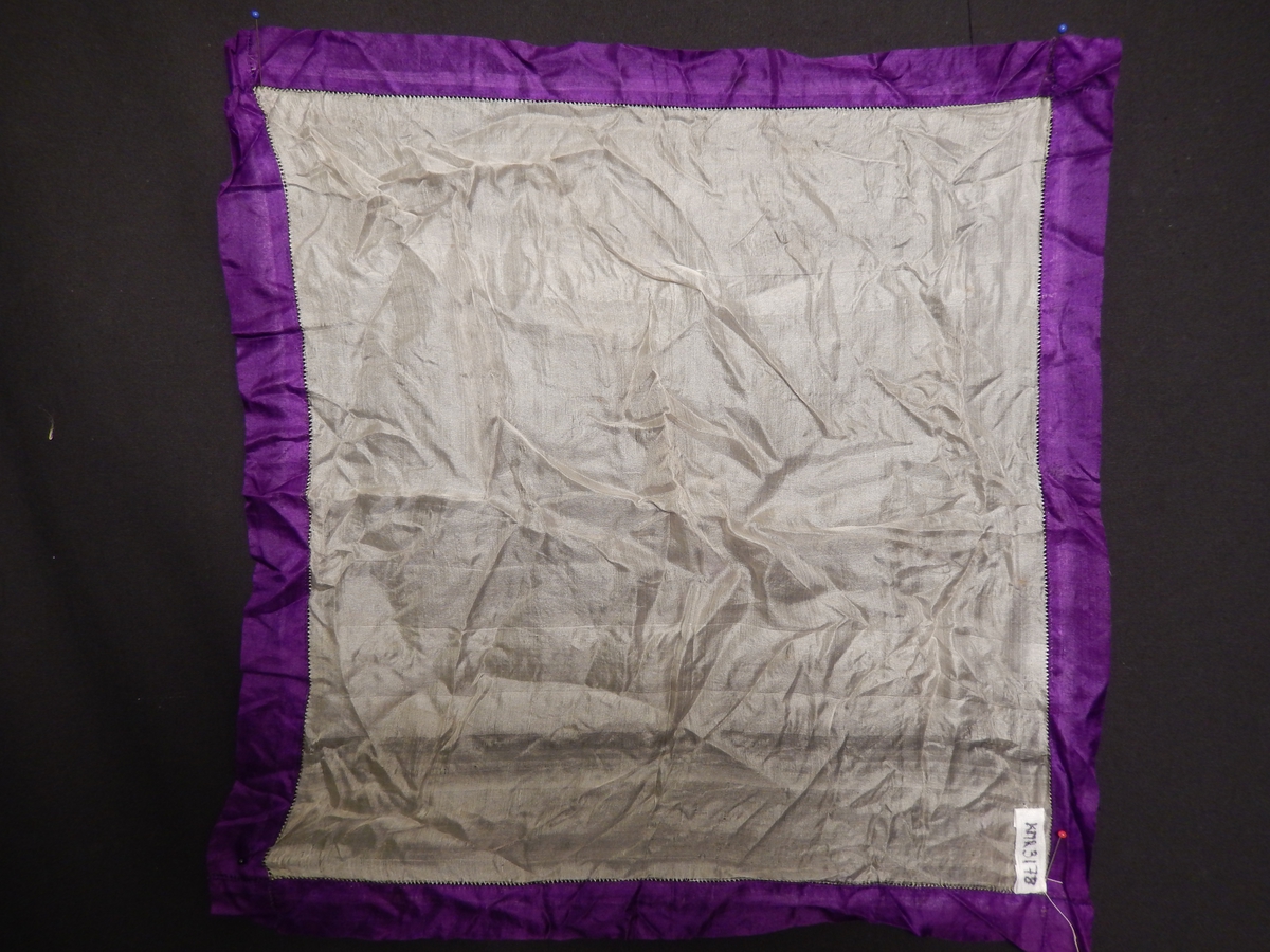 Lommetørkle, silke, tynt florlett stoff med påsydd lilla kant.