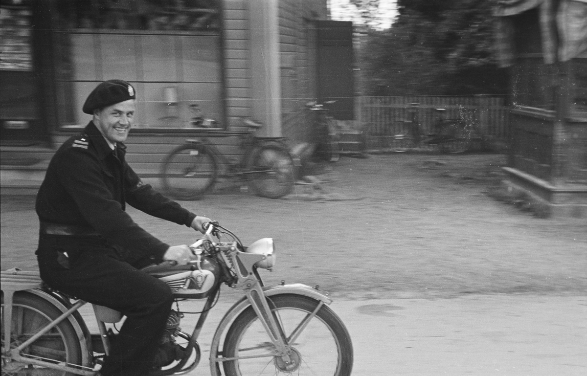Storgata, Leiret. Elverum. Uniformkledd mann på moped. 