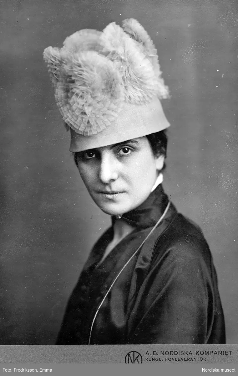 Kvinna i hatt med cirkelformade applikationer av tyll.