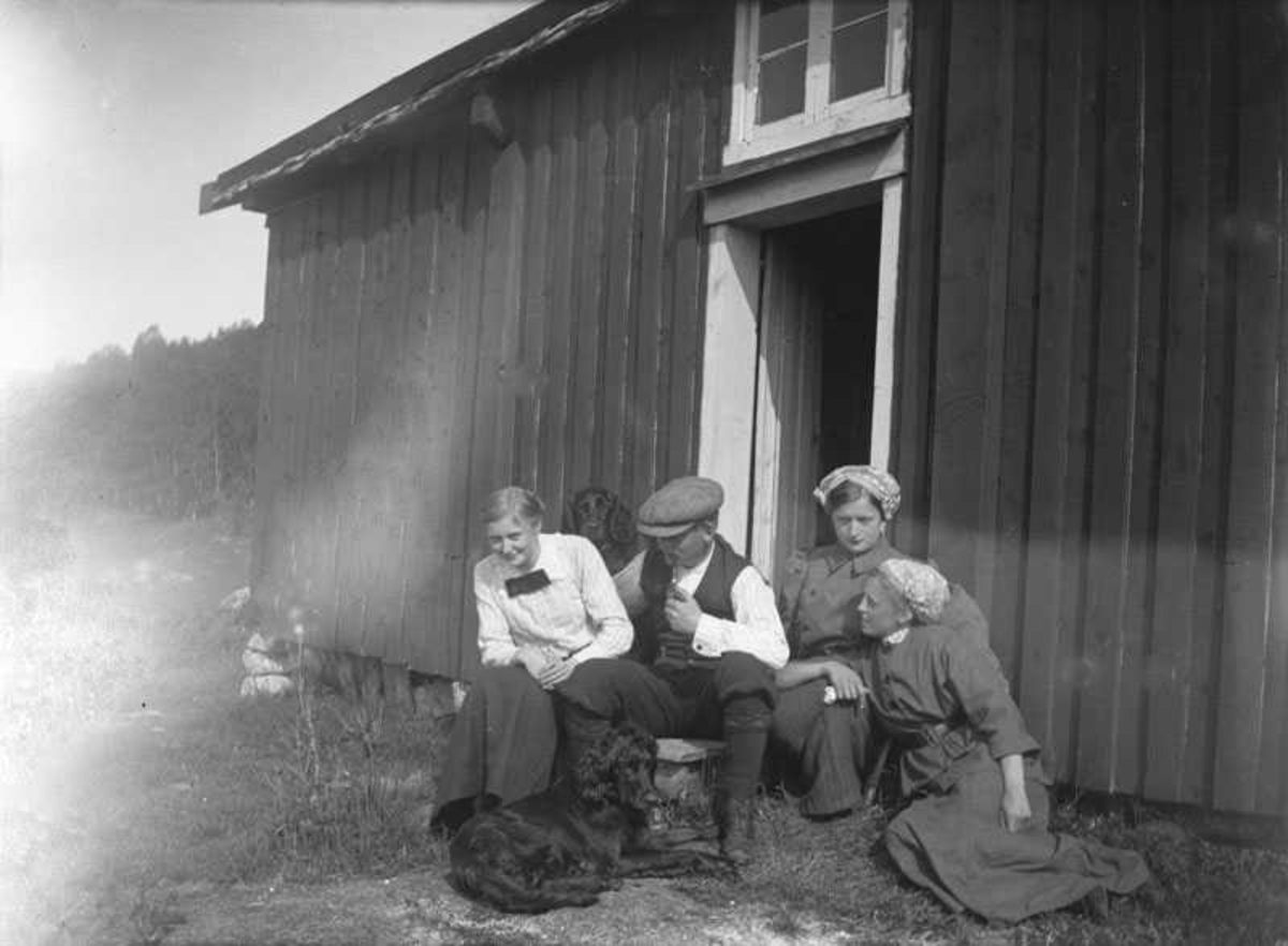 3 damer, 1 mann og 2 hunder på trappa. Aagot Olaussen sitter på gresset foran, de tre andre er søsken fra Petersenfamilien.
