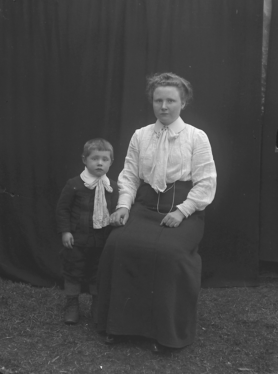 Portrett. Annie Pedersen, opprinnelig fra Værøy, sammen med sin sønn Bernhard Pedersen. 
Bildet er tatt på Ramberg i Lofoten.