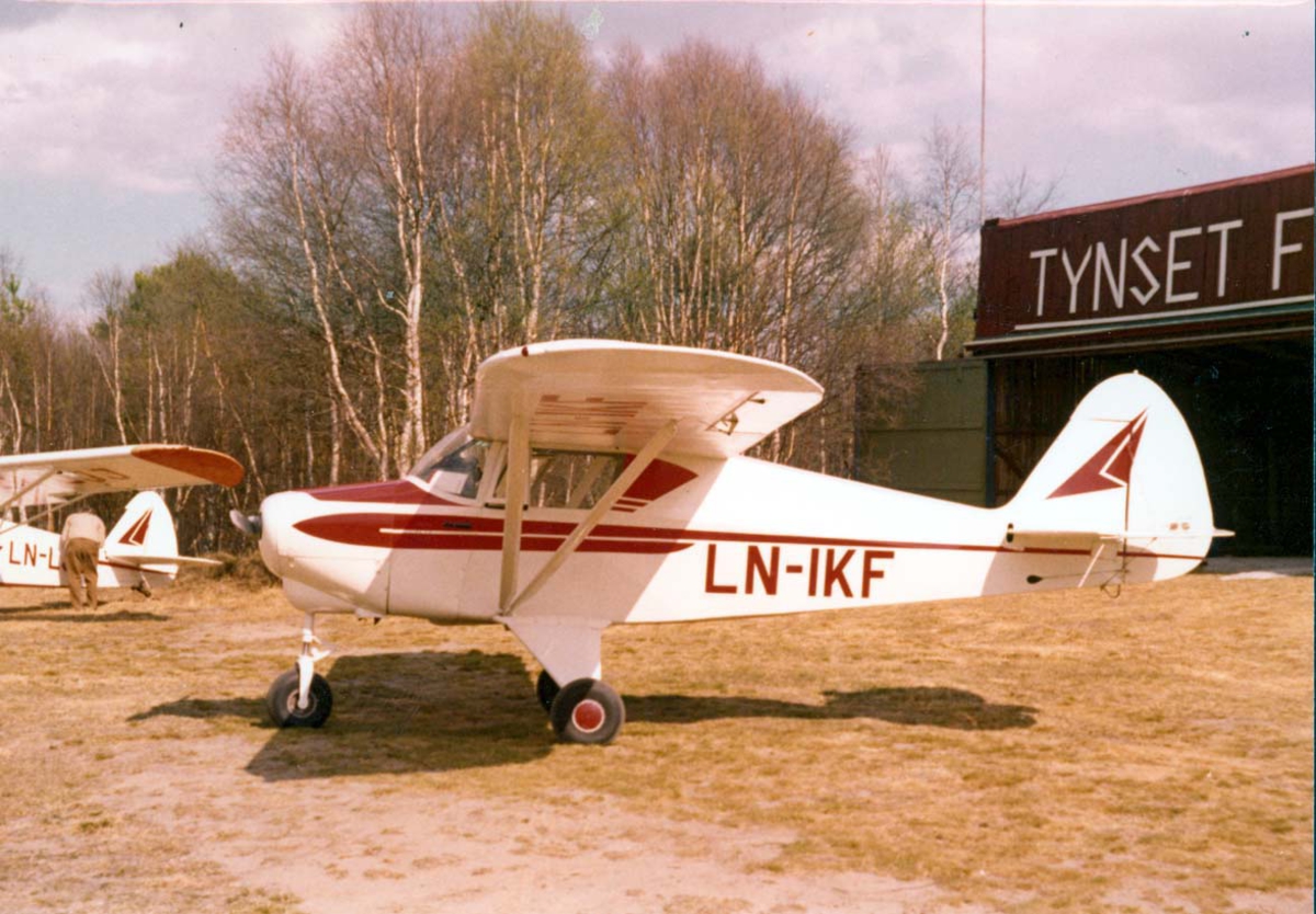 1 fly på bakken, Piper Colt PA-22 LN-IKF. I bakgrunnen bygning med skilt - påskrift "Tynset flyklubb