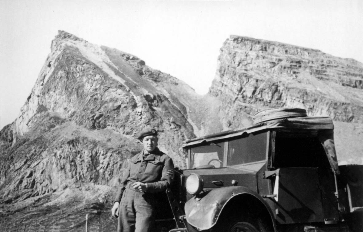 Portrett. 1 person, mann i militæruniform ved et kjøretøy