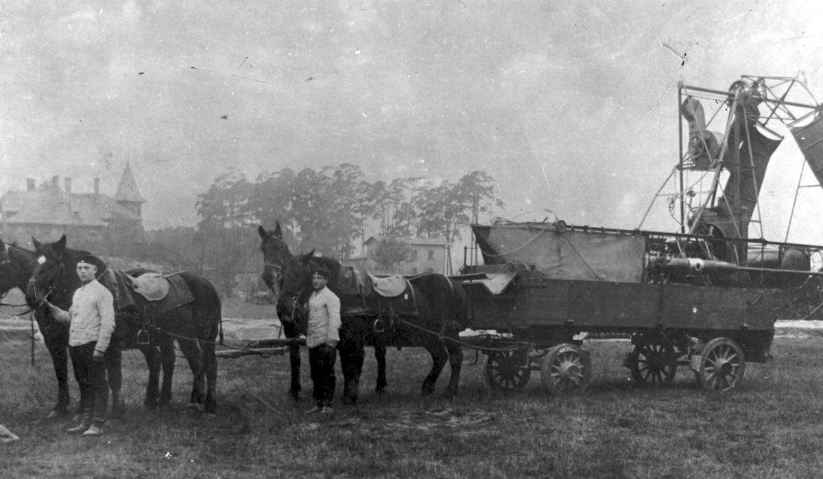 To hester drar ei vogn lastet med diverse utstyr til ett luftskip, Parseval P.L.1. To personer, menn ved hestene