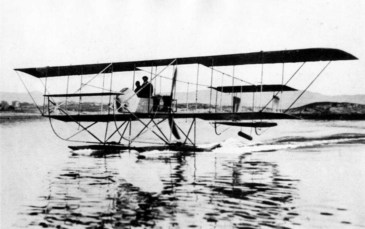 Ett fly i sakte fart på vannet, Farman S.3 Longhorn. To personer i cockpiten