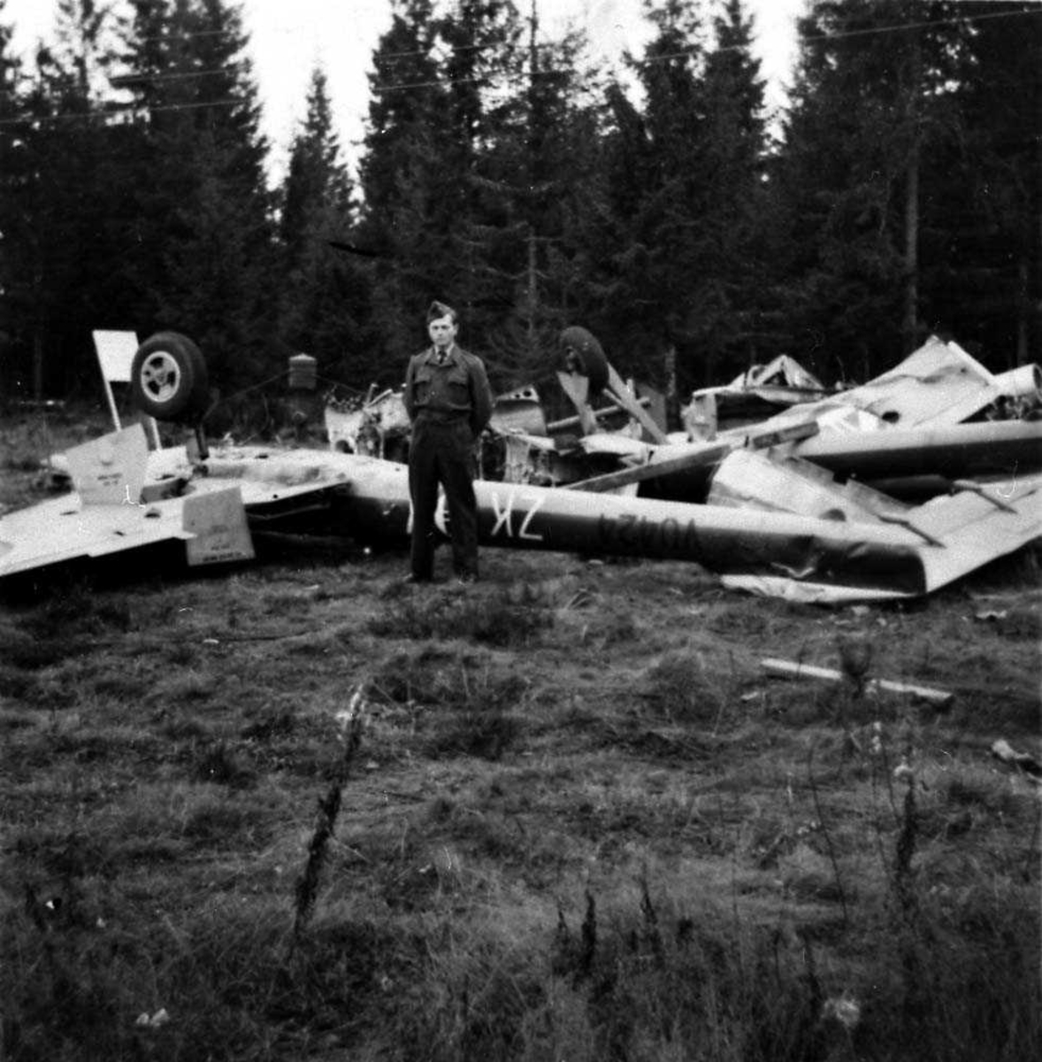 Ett fly som ligger ødelaget ute i en skog etter et totalhavari, Vampire FB Mk 52. En person står foran flyet.