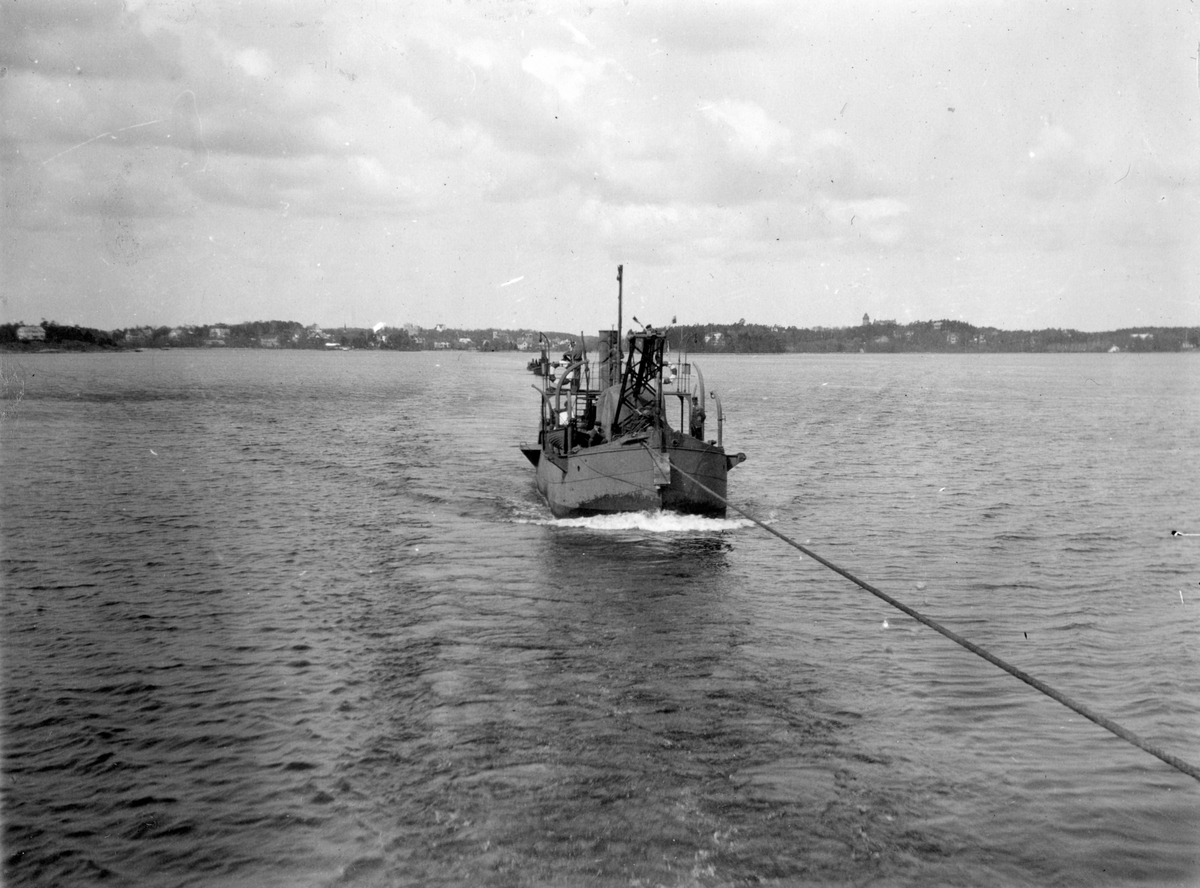 Bogsering av båt med hjälp av en lina till sjöss. I bakgrunden syns land.