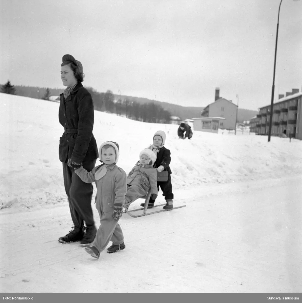 Sundsvallshems mammor och barn på promenad. De nybyggda flerbostadshusen i kv Vinkeltået syns i bakgrunden.