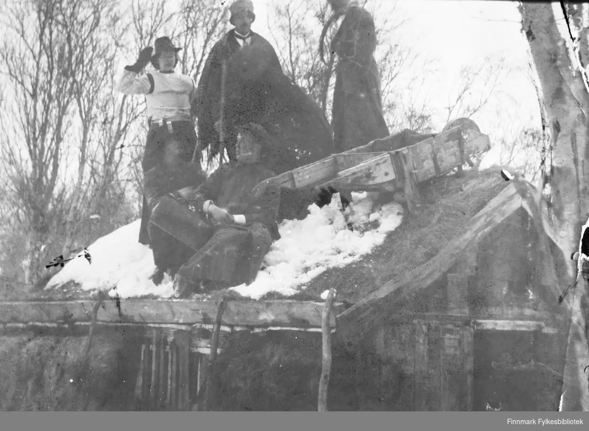 Ungdommelig tull i Tana, ca. 1916. Personene på bildet har kledd seg ut og dratt en trillebår opp på et tak, der de har blitt fotografert