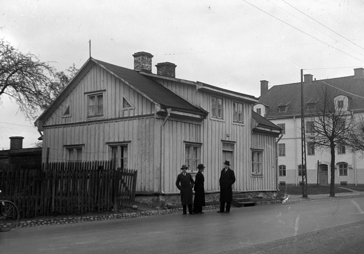 Tre män står framför ett bostadshus av trä vid Barnarpsgatan 100 i Jönköping. Det var ett utvärdshus en gång i tiden, kallat Glada Livet, men numera flyttat till Hovslätt.