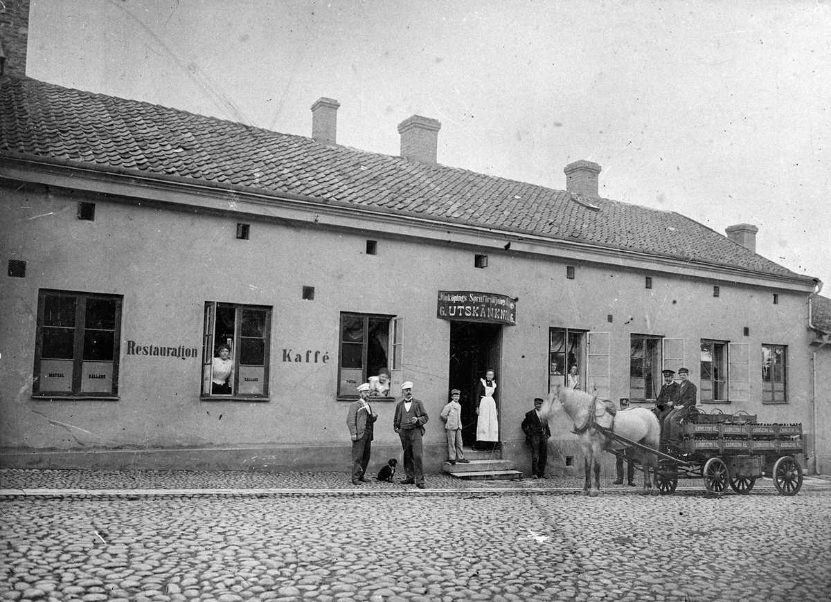 På Barnarpsgatan i Jönköping står häst och vagn utanför "Tummakrogen". Det är Restauration och Kaffé med Utskänkning, matsal och källare. På skylten ovanför dörren står texten: Jönköpings Spritförsäljngs... 6. Utskänkning 6. Människor på bilden är Torsten Johansson (1891-1961), innehavare av Johanssons åkeri (Braheg. 6), Anders Gustav Johansson (1863-1930) var åkeriägare och kusk vid Sandvalls järnaffär samt Lovisa Johansson (f. Andersson) (1855-1925), syster till Anders.