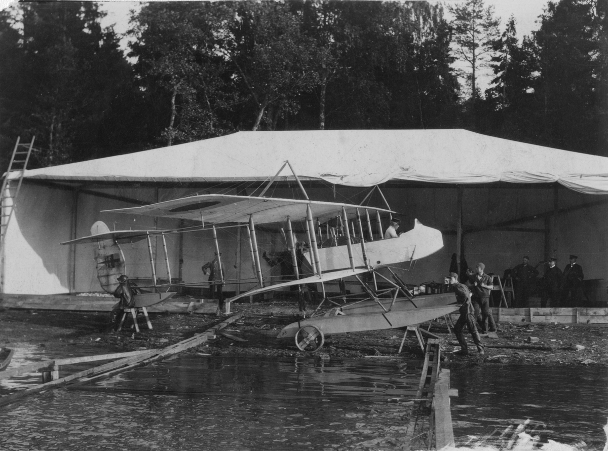 Flygplan Farman HF 23 med flottörer på vatten framför tälthangar vid Dalarö.