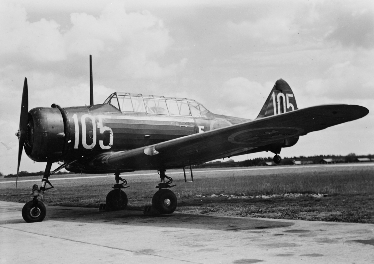 Flygplan SK 14 märkt nummer 105 med noshjul tillhörande Krigsflygskolan F 5 står på ett flygfält. Sidovy.