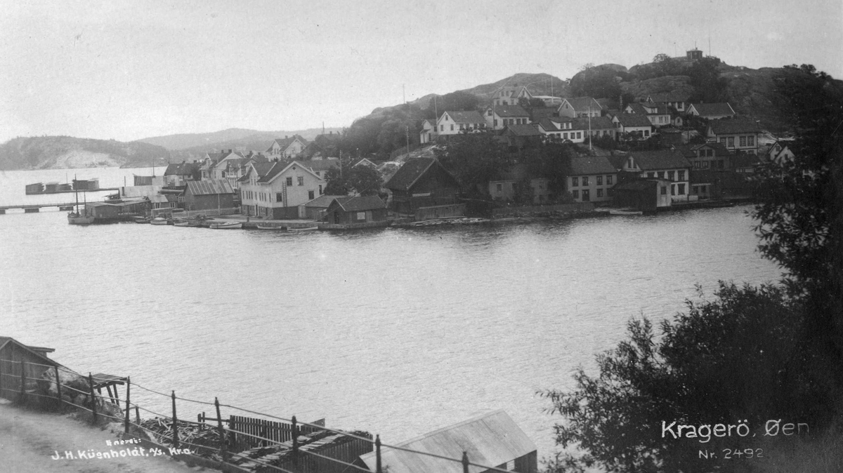Fra Barthebrygga mot Øya. Bebyggelsen på Øya vestre. Kornboden, kommunehuset og pontongbrua. Ca. 1920.
