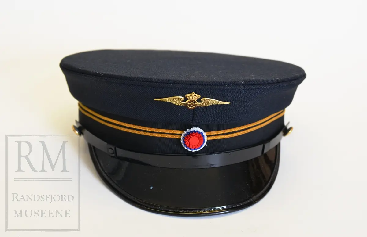 Uniformslue fra NSB, trolig 1970-tallet. To gullsnorer, rosett i rødt, hvitt og blått