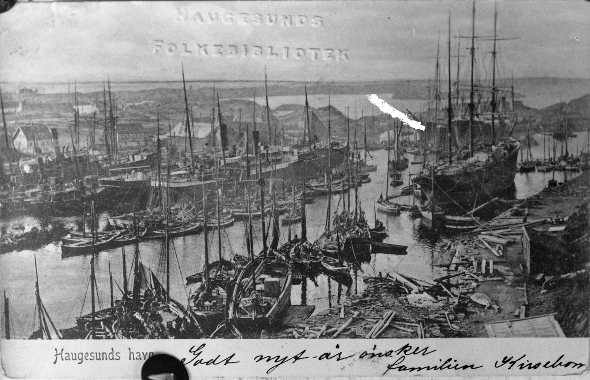 Sildefiske ved Haugesjøen, ca. 1900. Mange fiskebåter, robåter og en stor seilskute ankret opp til høyre på bildet. Noen dampskip ankret opp på motsatt side (Hasseløy). Sjøhus i bakgrunnen på Hasseløy. Andre seilfartøy lengst til høyre i bakgrunnen.