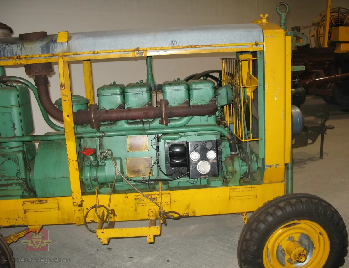 Transportabel kompressor, 2-akslet, har 4 hjul, I hovedsak grønn og gul. Bygd inn med vegger og tak. Drag i fronten, trykktank, (datert 8.6.56), og dieseltank i bakkant. Maskina har en 4-sylindret dieselmotor fra R. A. Lister, type 4-40,  som yter 40 Hk. Denne motoren driver Broom & Wade kompressoren. Merking fra produsenter og bruker.

