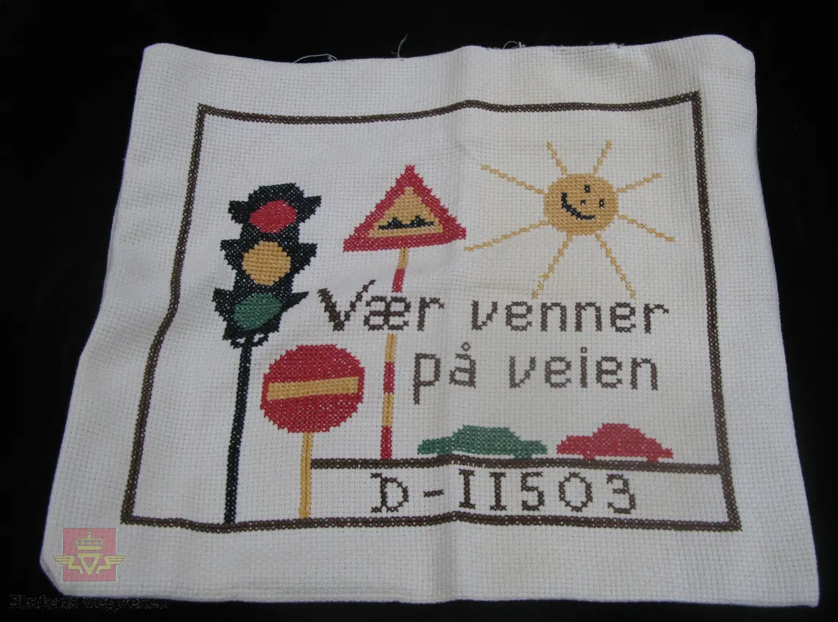 Putetrekk, hvitt med flerfarget broderi. Motivet viser ei sol, to trafikkskilt, en lysreguleringsenhet og to biler samt teksten " Vær venner på veien   D-11503".