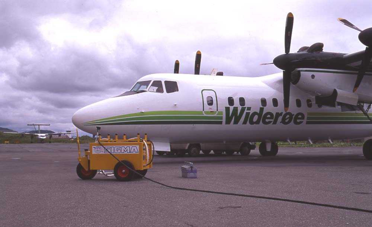Lufthavn/flyplass. Bodø. Widerøes hangar. To fly, LN-WFE, DHC-7-102/ Dash7 fra Widerøe parkert nærmest. I bakgrunnen nok en DHC-7-102. Bak denne skimtes flytårnet. 