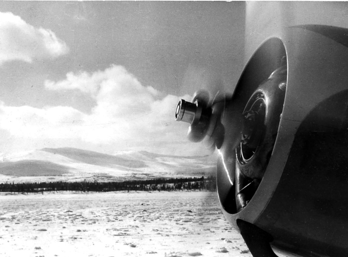Detalj av flymotor på en propellfly fra Widerøe. Åpen plass med snø på bakken.