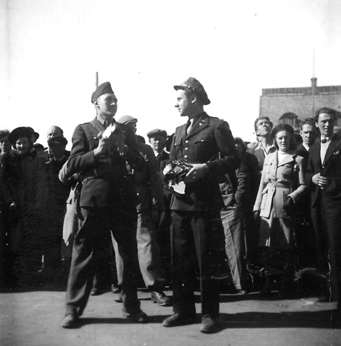 Frigjøringsdagene i Bodø etter krigen 1940 - 1945. En soldat og en offiser foran, mange personer bak.