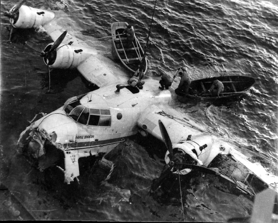 Ett fly, Short S.25 Sandringham 6. DNL.  LN-IAU "Bamse Brakar", delvis nedsunket i havet, en del skader,  Flyet heises opp, noen personer og åpne småbåter bak flyet.