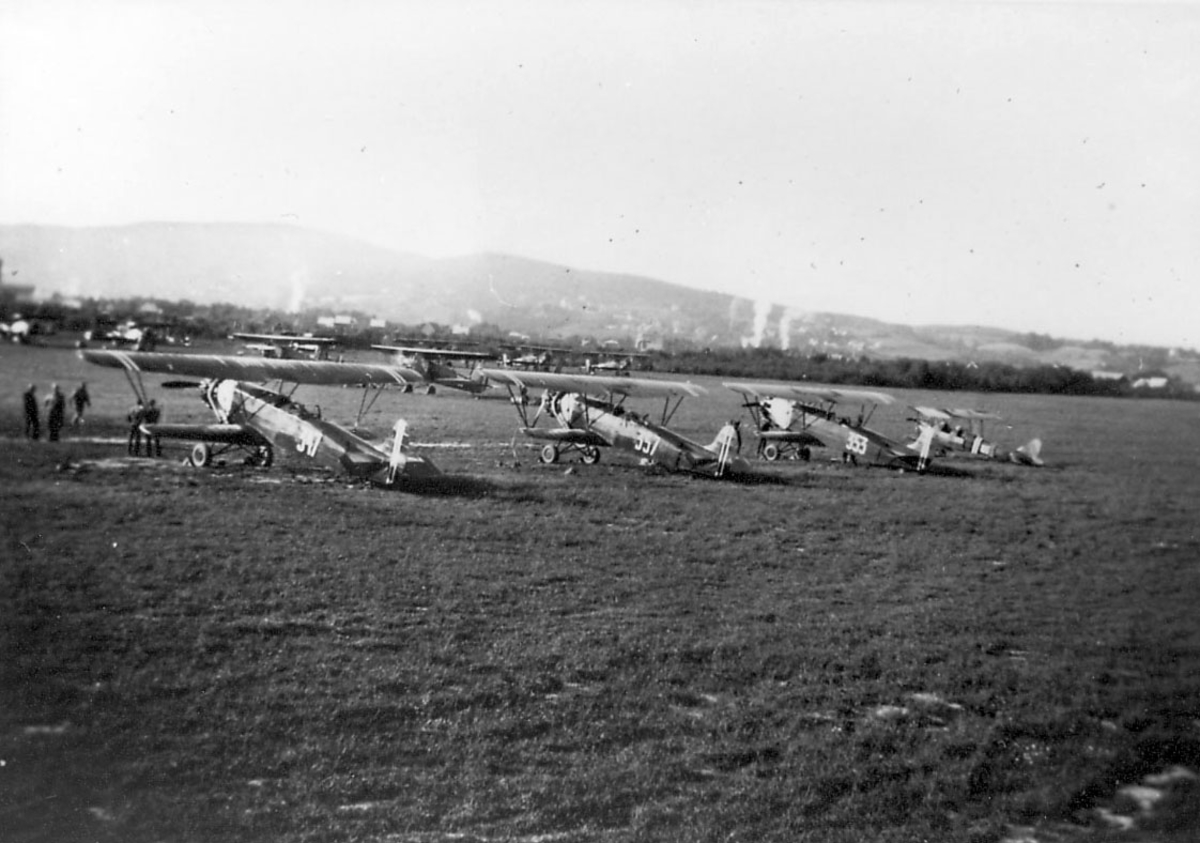 Åpen plass, lufthavn. Flere fly oppstilt, fra venstre; Fokker CVE reg.no. 347, Fokker CVD reg.no. 357, Fokker CVE2 reg.no. 353, De Havilland, Tiger Moth.