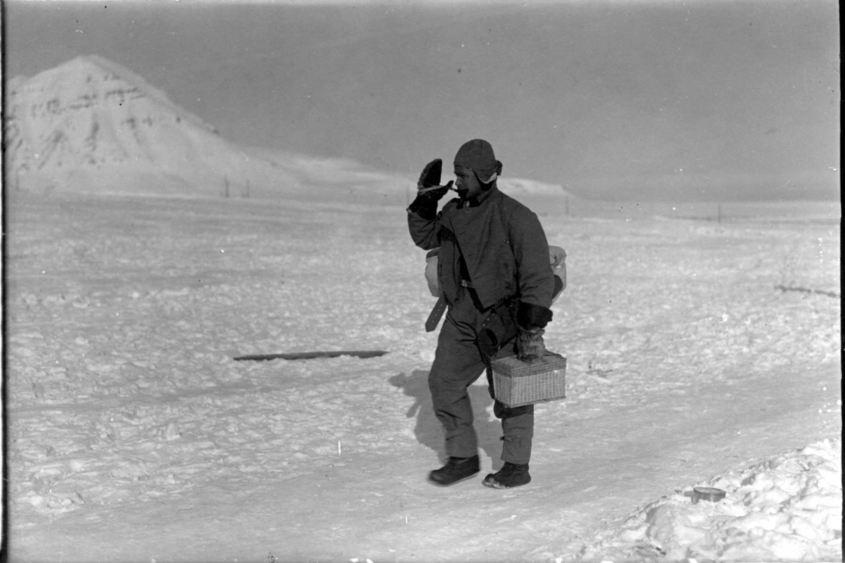 Portrett. En person, mann går på en "vei", og bærer på noe utstyr. Snø på bakken.