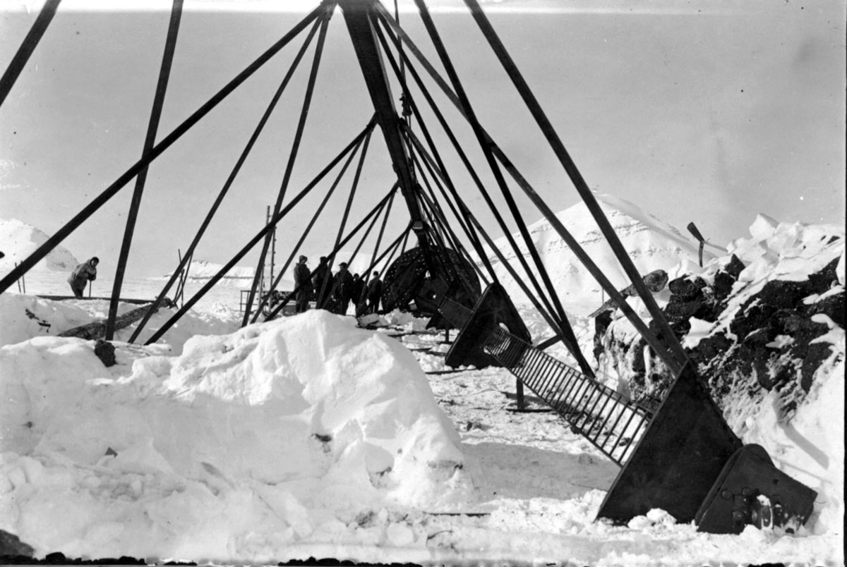 Fortøyningsmasten til luftskipet "Norge" før den heises på plass. Flere personer i arbeid. Snø på bakken.