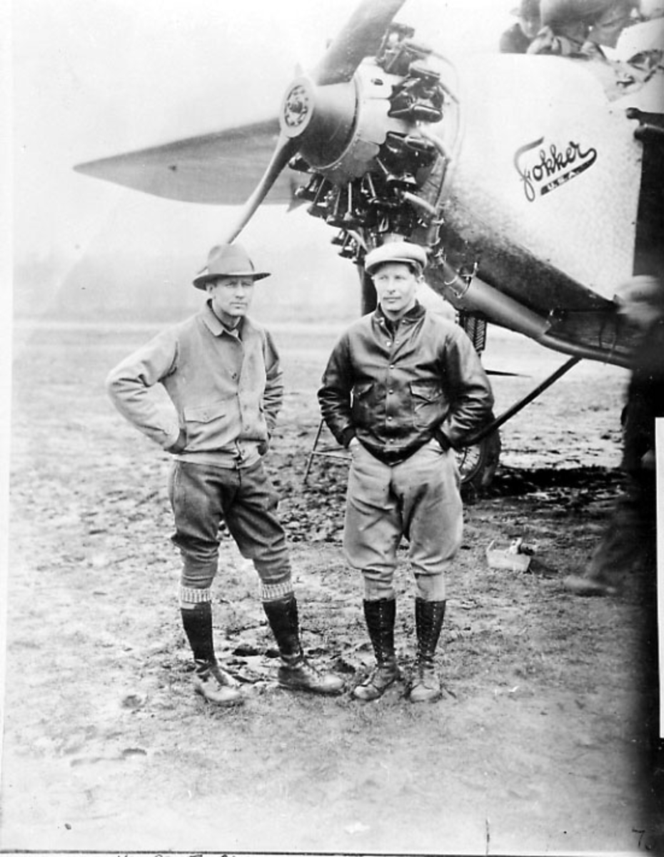 Portrett, 2 personer står foran nesepartiet på et fly - Fokker -. Tatt utendørs