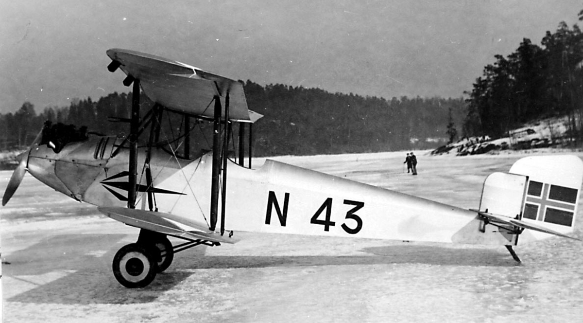 1 fly på bakken, islagt vann, Simmons Spartan I, N.43 LN-ABG fra Viggo Widerøe, Oslo. 2 personer i bakgrunnen.