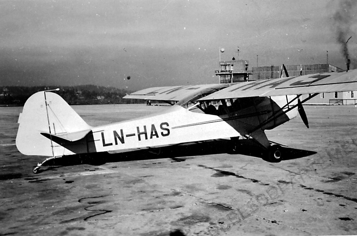 Lufthavn, 1 fly på bakken, Auster J.1, LN-HAS fra Lillehammer Fly. Kontrolltårnbygningen i bakgrunnen.
