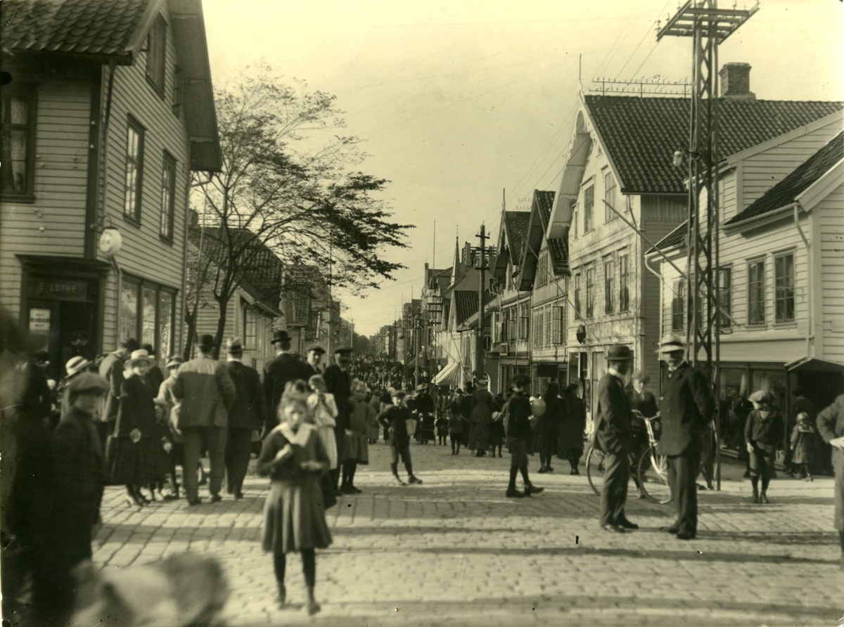 Prikkedag, Mikeli (29. sept.?) 1916.
S. Lothes bokhandel på hjørnet (gatekrysset Haraldsgt./Kaigt.). Mange mennesker samler. Brosteinbelagt gateløp.