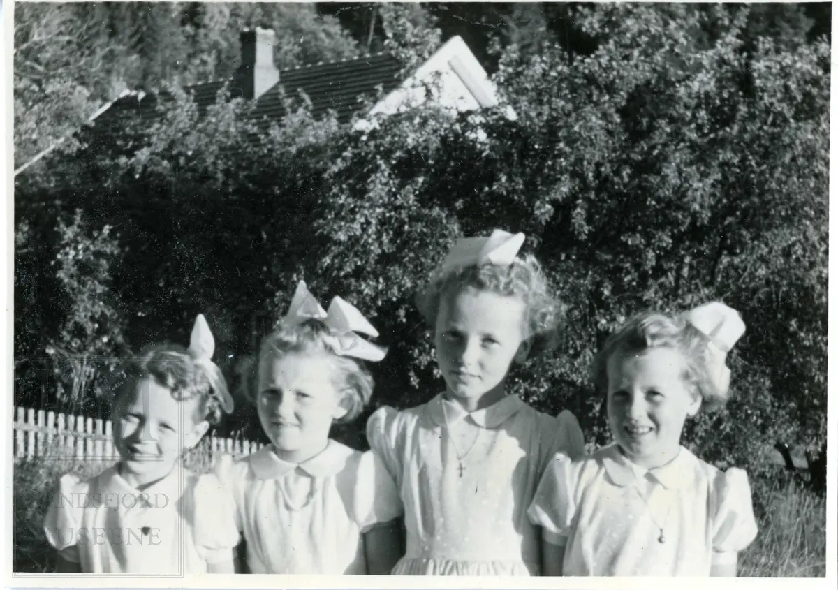 Fire jenter i kjole og sløyfe i håret.