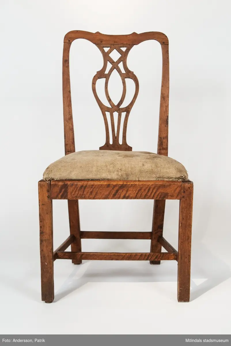 Stol, genombruten ryggbricka, raka ben med kvadratisk genomskärning. H-kryss samt slå mellan de bakre benen.Tillverkad i Lindome 1760-80-tal.Stolens ryggbricka återgår på en förlaga av den engelske möbelformgivaren Thomas Chippendale (verksam vid mitten av 1700-talet). Stolen har framtagen rödbrun originalfärg (vid förvärvet var stolen målad i en sentida gråvit lackfärg).Lös sits med originalsadelgjord och stoppning. Inköpta av Per Falck, intendent vid Nordiska museet, för Mölndals museums räkning av antikhandlare Bengt Jansson i Älmhult.En stol stulen 2002.