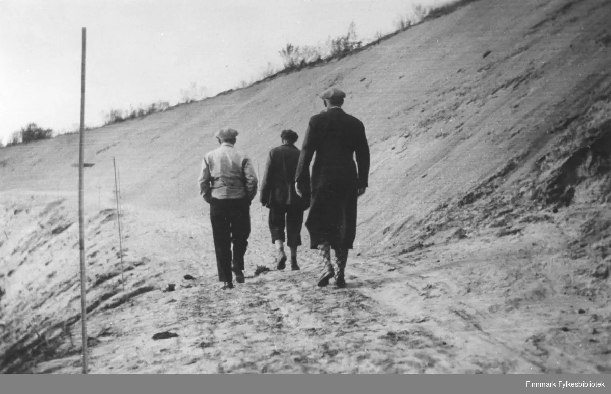 Ved Neiden bru. Man ser fra venstre Wilhelm Kling, Knut Fixdal og Jakob Natvig Matzow som går bortover veien med ryggen til fotografen