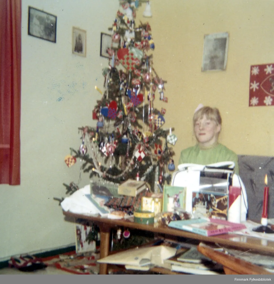 Vanja Larsen sitter ved siden av et juletre i Syltefjord. På veggen henger det flere bilder og på bordet kan man se flere gjenstander, blant annet et talgelys. Juletreet er pyntet med julepynt. På venstre hjørne av bilde kan man skimte et par sko.
